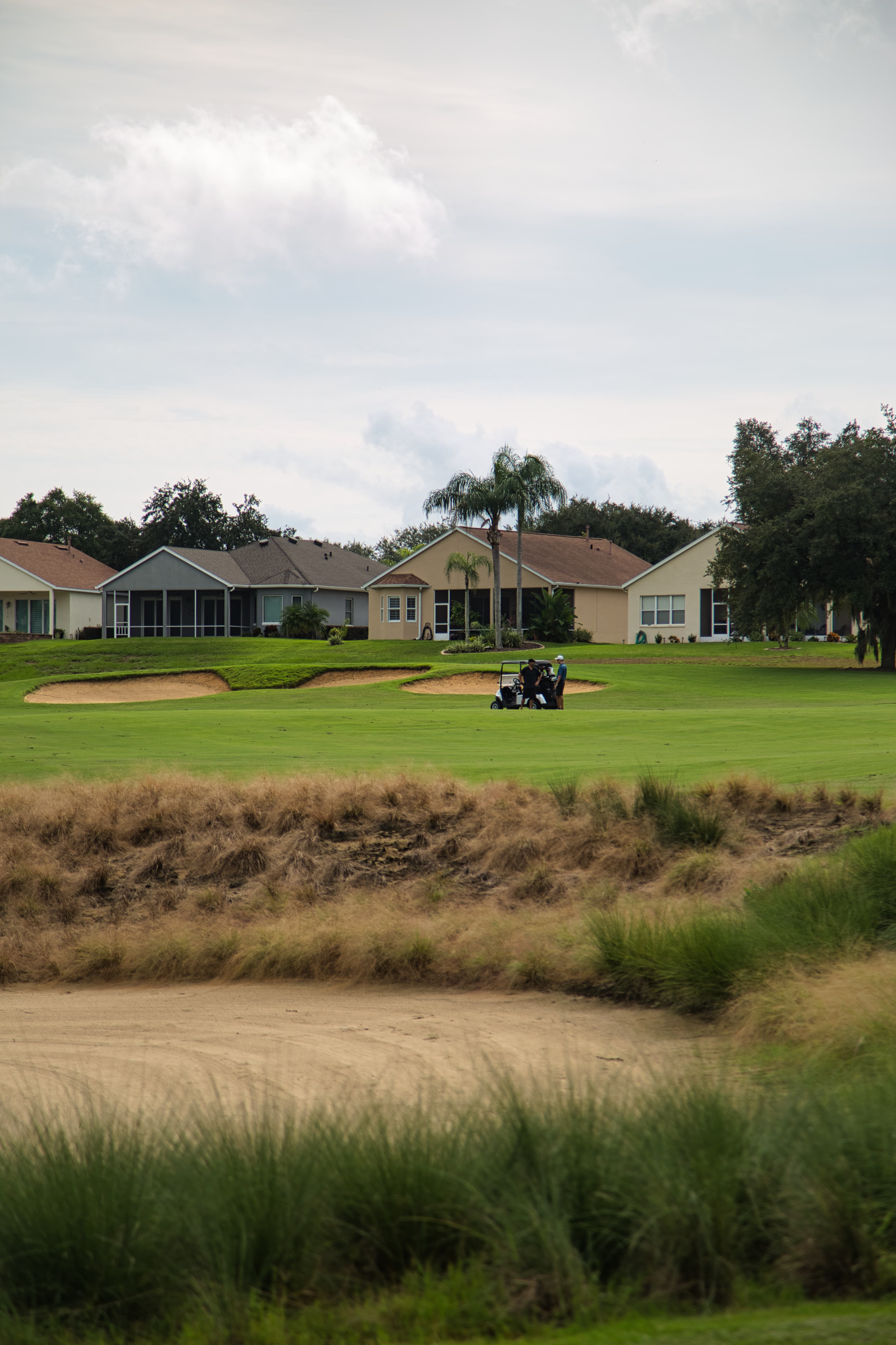 Golf cart near greenside bunker on a lush Clermont National hole